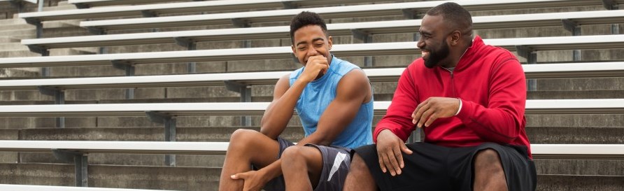 two-males-sitting-bleachers-laughing-other-adults